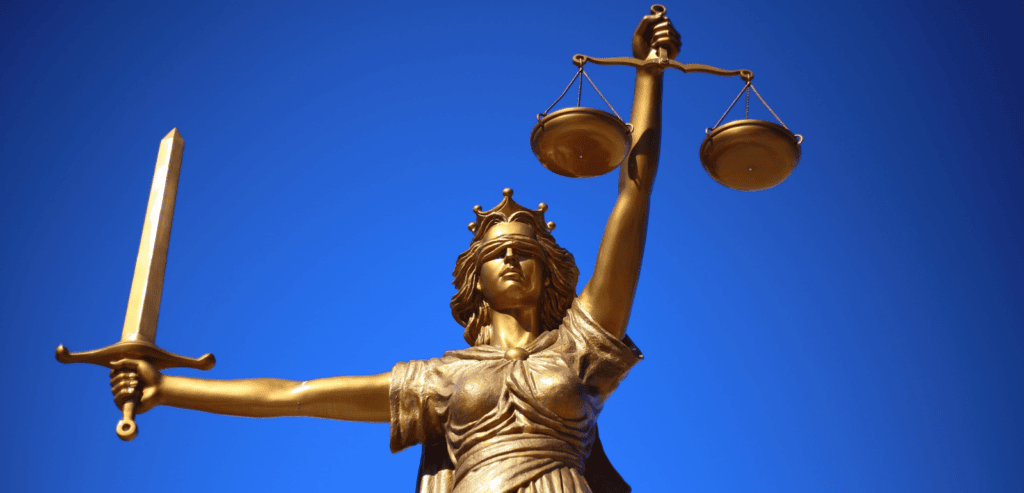 A golden statue of Justice, wearing a blindfold and holding a sword in one hand and weights in the other. Set against blue background.