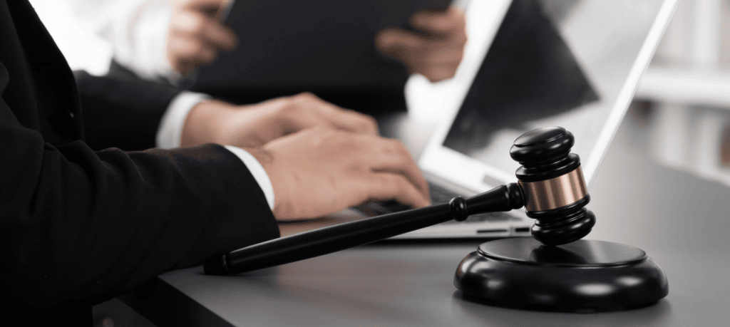 Two lawyers use laptops at their practice. Gavel in forefront of image.