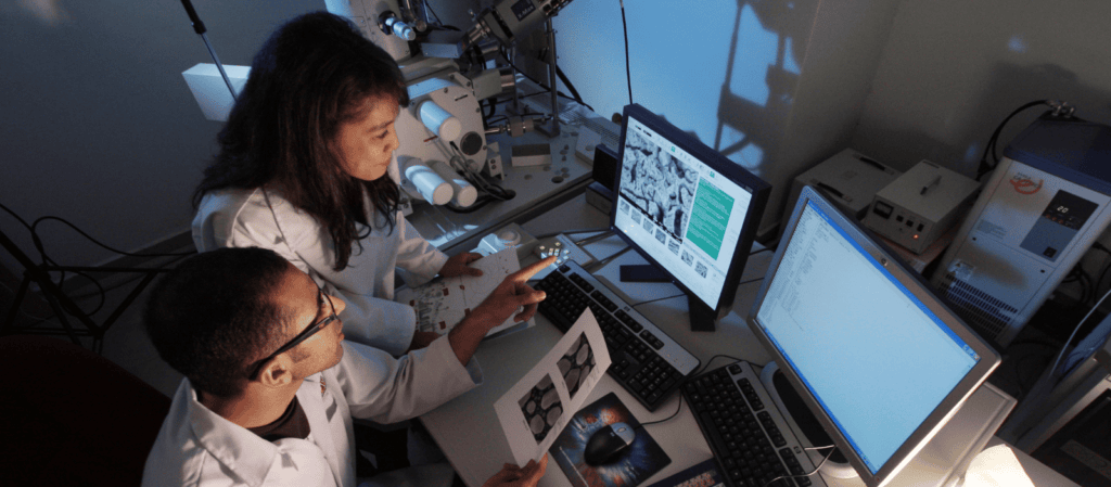 Two scientists use a computer to compare notes.
