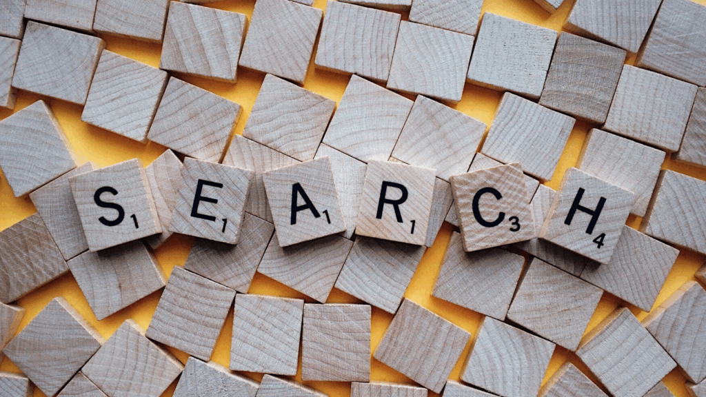 Scrabble tiles spelling "SEARCH" lay across a yellow background.