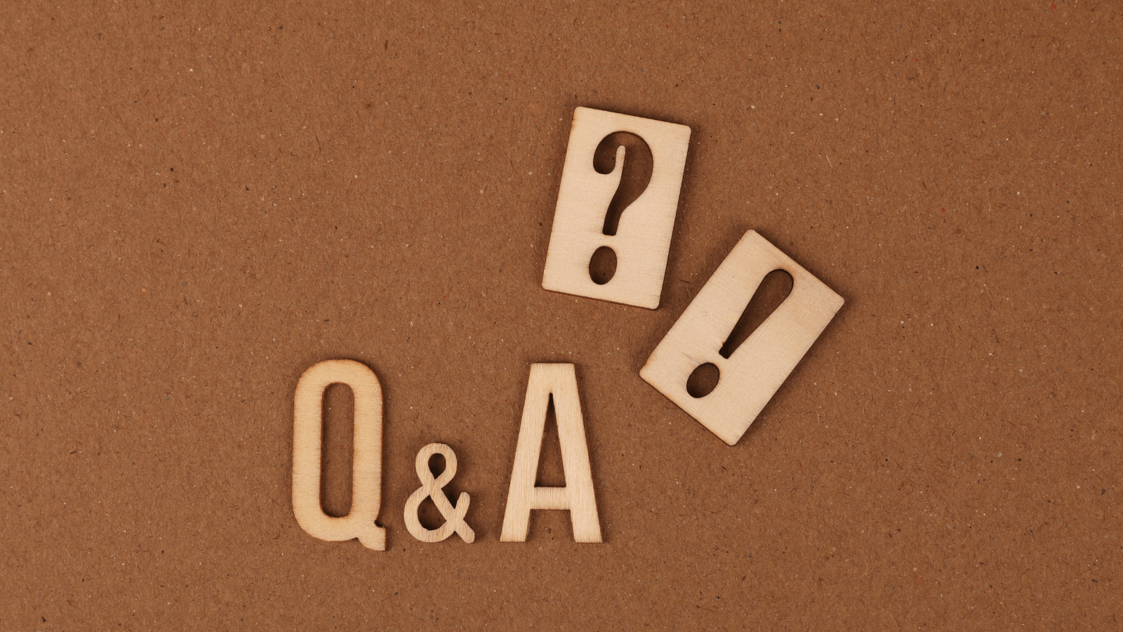 Wooden "Q & A ?!" cutouts set against corkboard background.