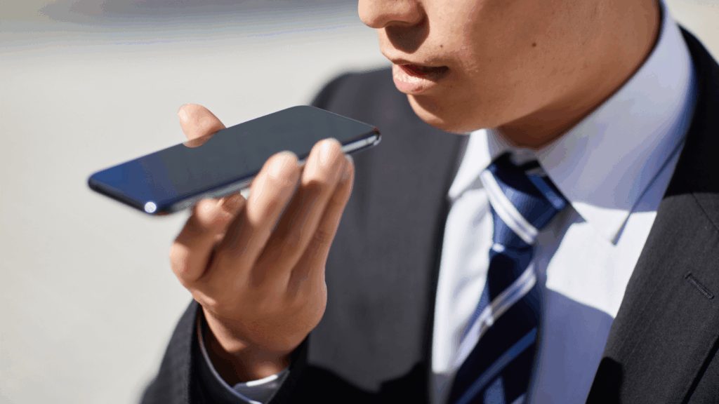 A person in a suit speaks into his phone to conduct a voice search.