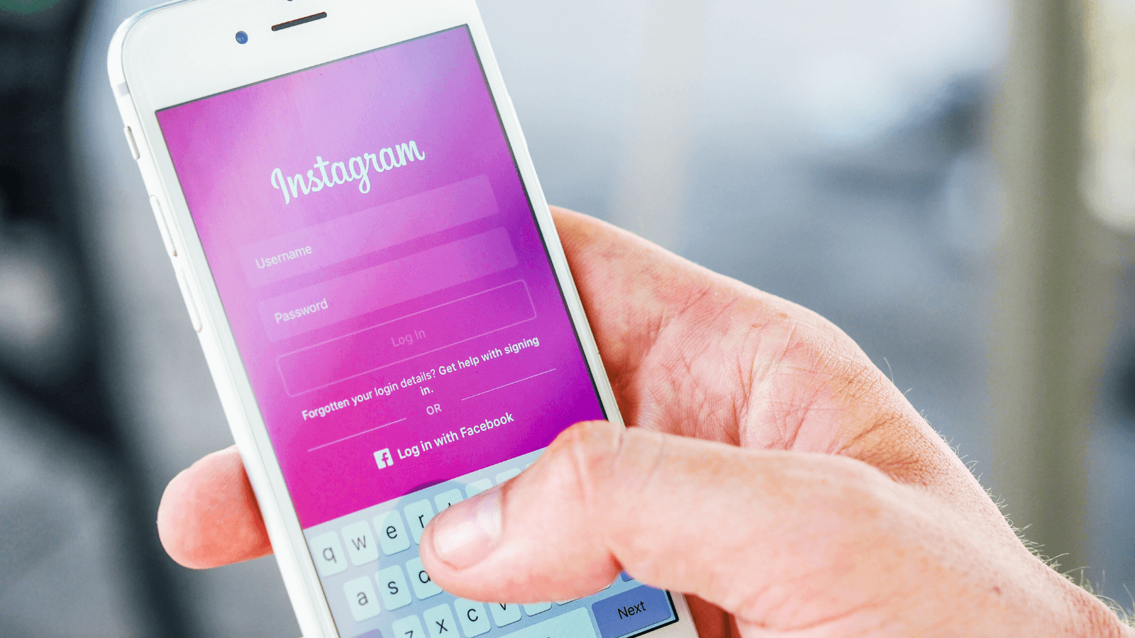 A person holds a cell phone displaying the Instagram login page.