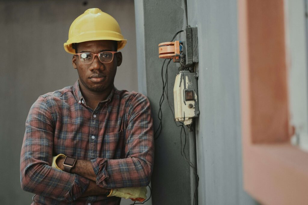 Portrait of a commercial field services architect at a building site looking at camera, wearing a hardhat and eye goggles. From Emmanuel Ikwuegbu on Unsplash.